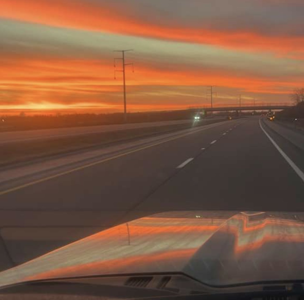 Uma rodovia ao pôr do sol, vista pelo para-brisa no caminho de casa.